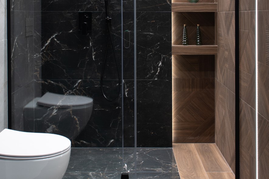 Czarne płytki z imitacji marmuru w strefie prysznica połączone z płytkami drewnopodobnymi