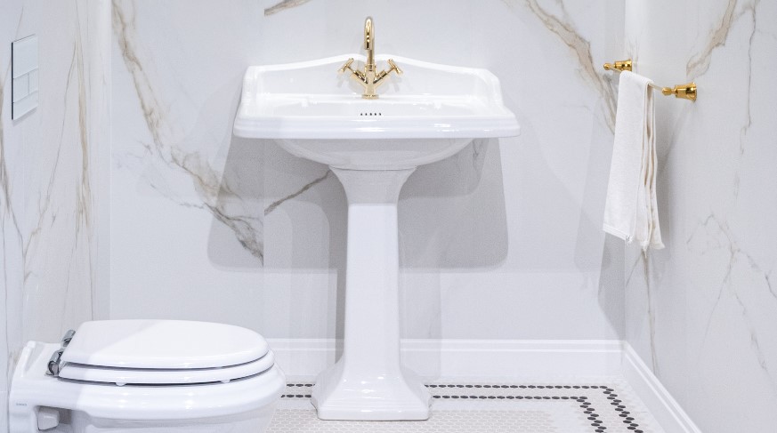 Łazienka w płytkach imitacji marmuru ze złotymi dodatkami glamour