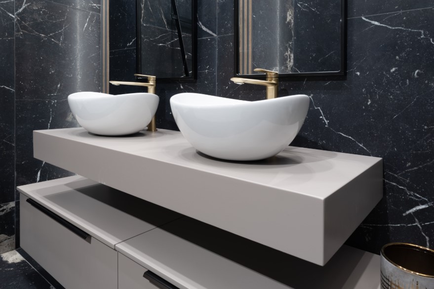 Białe umywalki nablatowe o nietypowym kształcie w czarno-białej łazience dla pary
