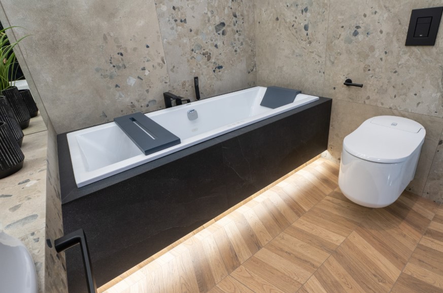 Antracytowa zabudowa wanny z hydromasażem płytkami imitującymi kamień.