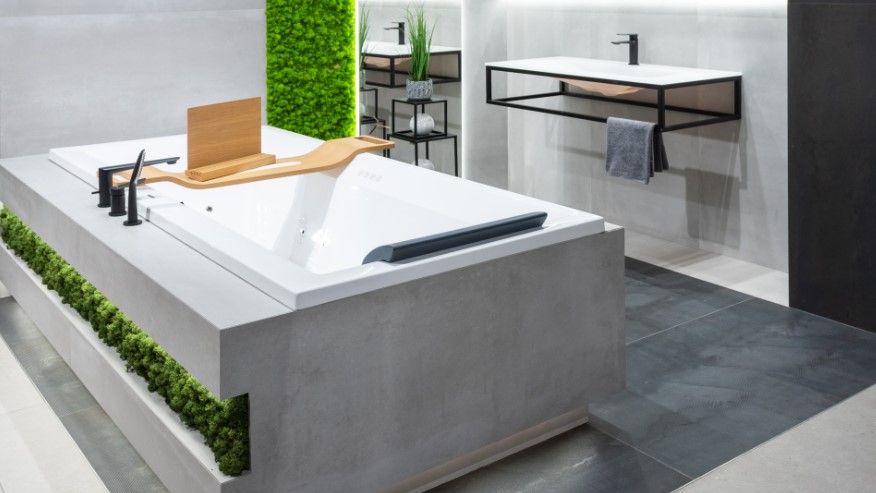 Łazienka w industrialnym stylu z wanną zabudowaną płytkami imitującymi beton.